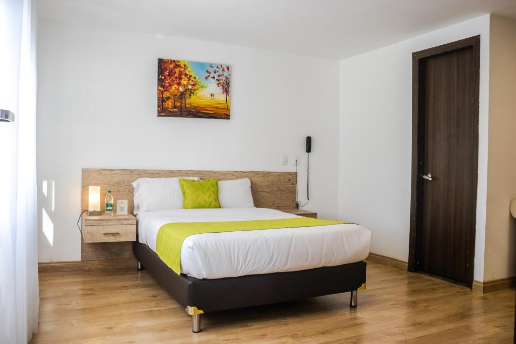 a bedroom with a large bed with yellow and white sheets at Nogal Suite Hotel Ipiales in Ipiales