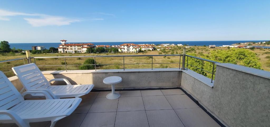 un balcón con 2 sillas, una mesa y el océano en Villa Una 7C en Lozenets