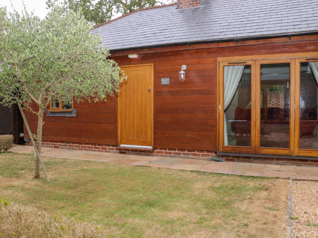 a wooden house with a door and a tree at Squirrels Drey in Fareham