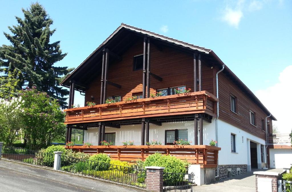 a large wooden house with a balcony at Ferienwohnung Rhönblick in Hilders
