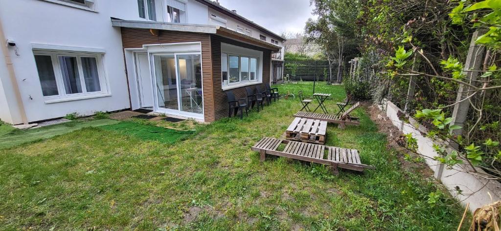 two benches in a yard next to a house at Vie Agréable JARDIN GRANDE CUISINE SALON 2 CHAMBRES in Soisy-sous-Montmorency