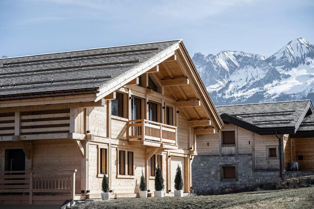 a large wooden house with mountains in the background at Chalet Zenspace in Le Grand-Bornand