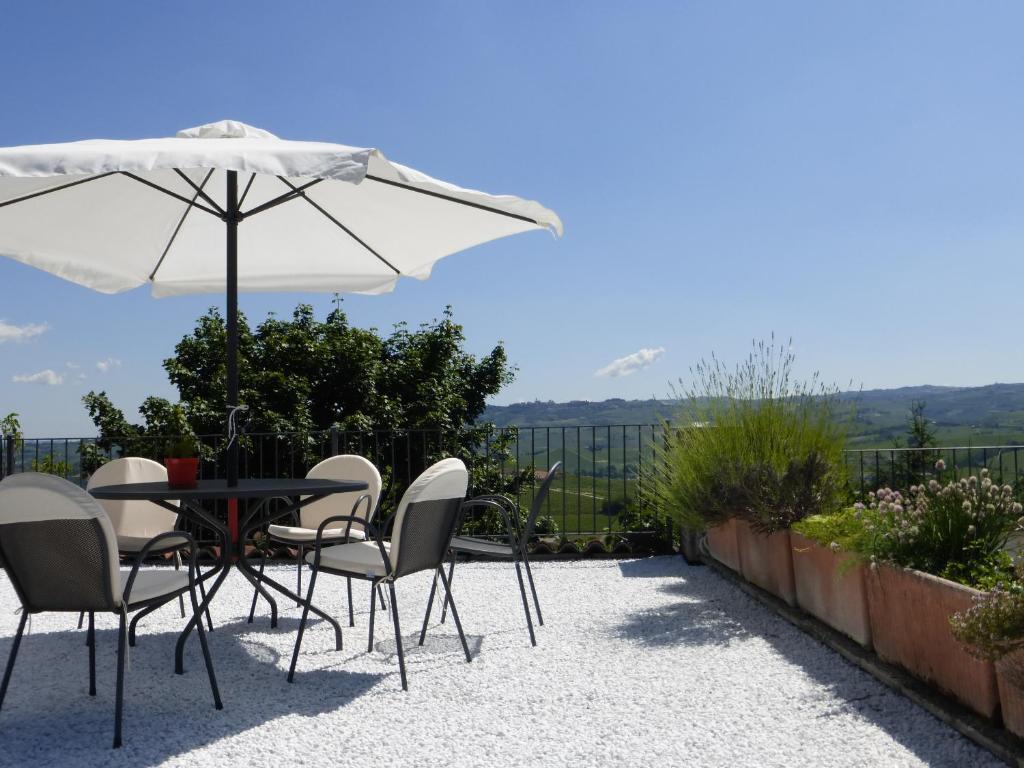 una mesa y sillas con una sombrilla en el patio en Agriturismo Erbaluna, en La Morra