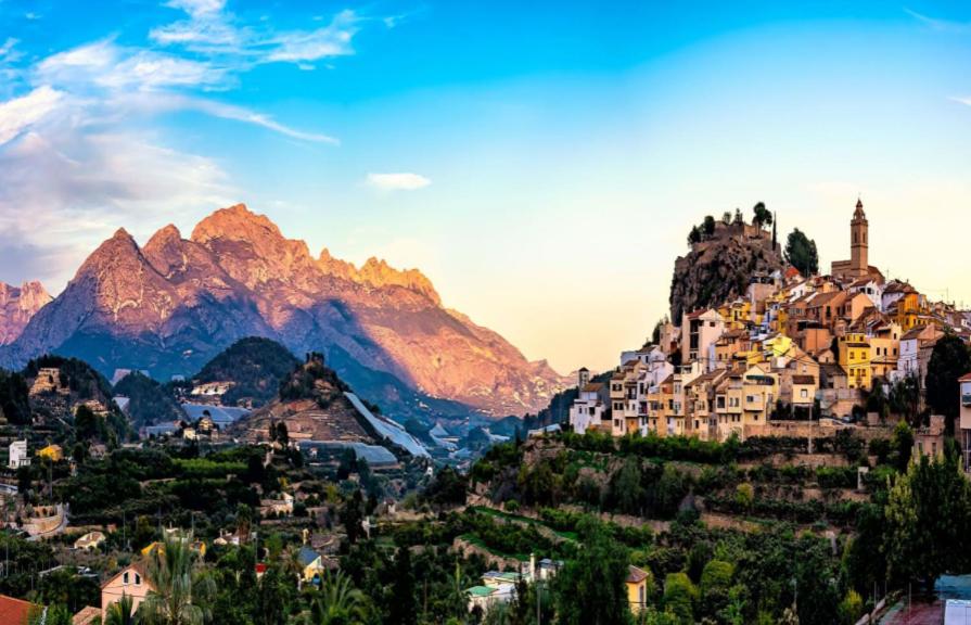 una ciudad en una colina con montañas en el fondo en BOTANIQ, en Polop