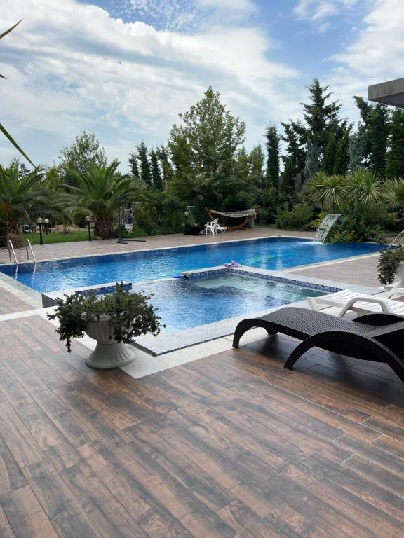 a large swimming pool in a yard with a wooden deck at Baku White Villa in Baku