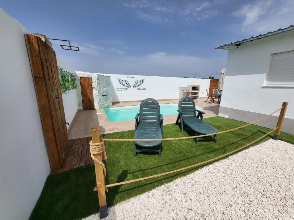 a backyard with chairs and a swimming pool at Villa Romadian in Chiclana de la Frontera