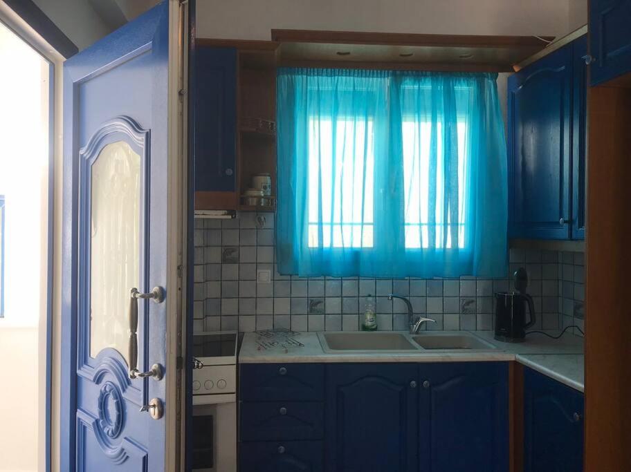 a blue kitchen with a sink and a window at Apollon Sunrise in Apollon