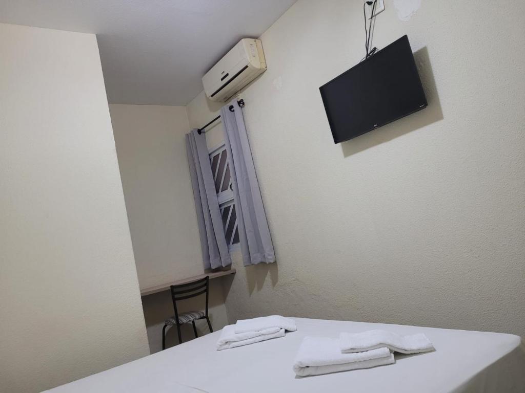 Cette chambre dispose d'une table blanche et d'une télévision murale. dans l'établissement BIGS HOTEL, à Penápolis