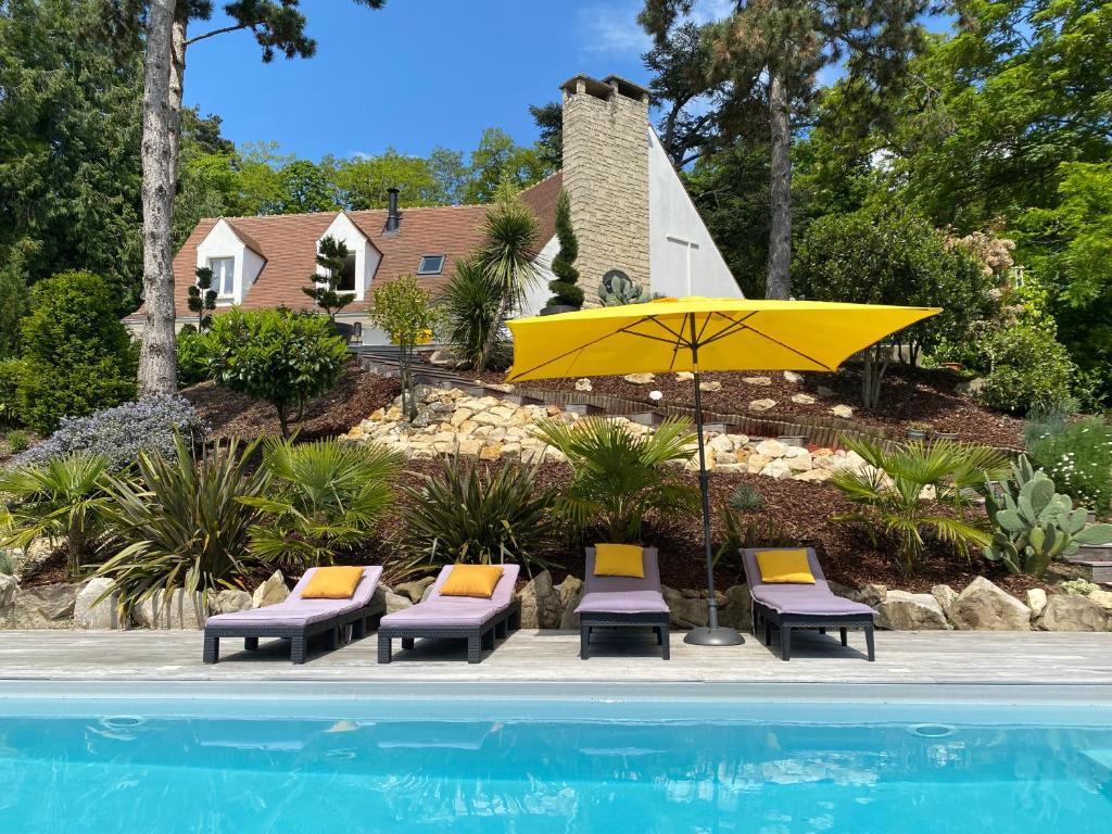 a yellow umbrella and chairs and a pool at appartement indépendant avec piscine in Saint-Prix