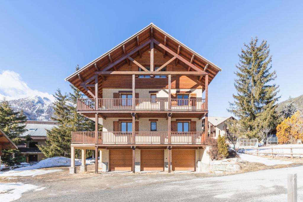 a log home with a large deck and mountains at Chalet Clos Gauthier in La Salle-les-Alpes