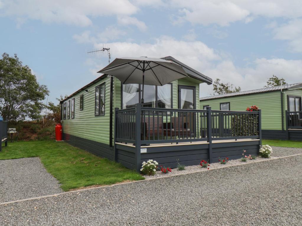 a green caravan with an umbrella on a porch at Jean's Place in Ganton