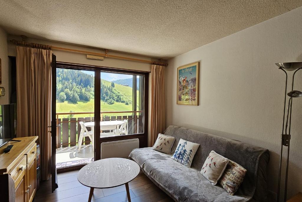 a living room with a couch and a balcony at 3-star apartment with view in La Clusaz