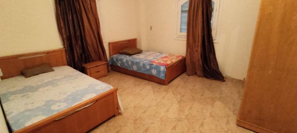 a small bedroom with two beds and a window at شاليه ٢٩ لا ارضي غرفتين اللوتس الساحل الشمالى in El Alamein