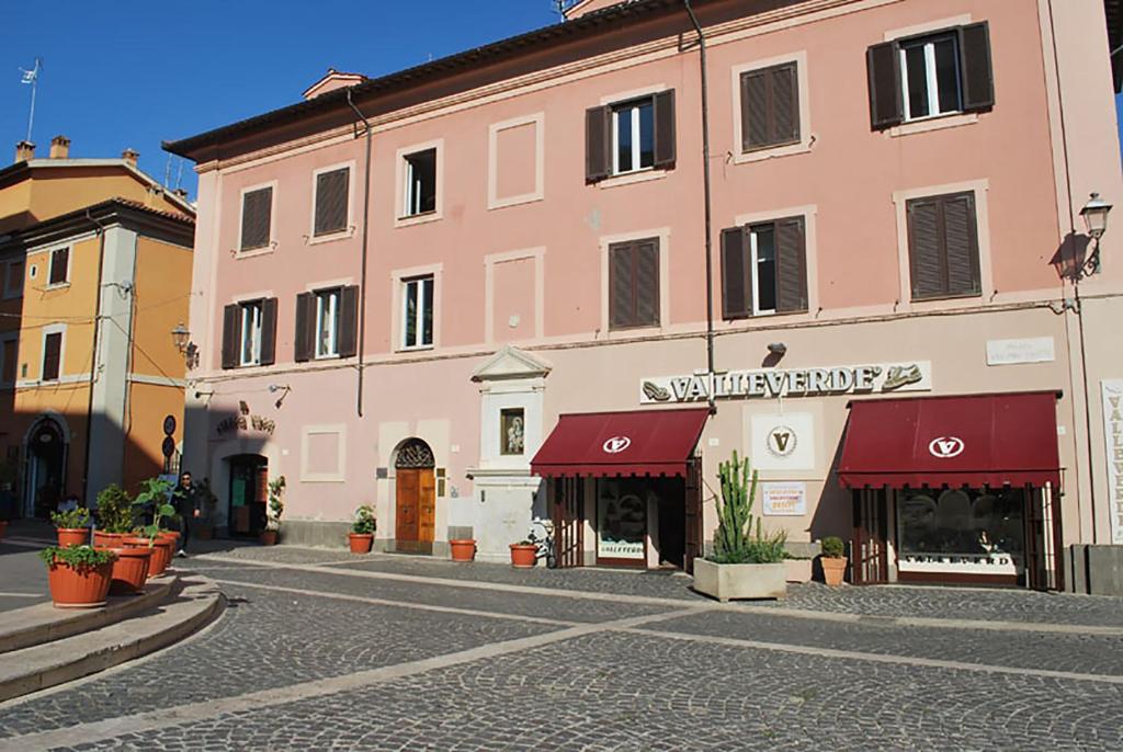 ein großes rosafarbenes Gebäude mit einem Geschäft in einer Straße in der Unterkunft B&B Piazza Fratti in Civitavecchia