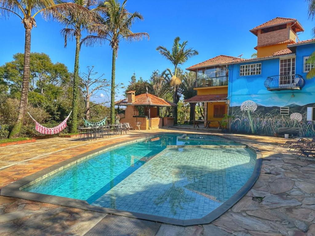 a swimming pool in front of a house with palm trees at Mirante do Espinhaço in Itabirito