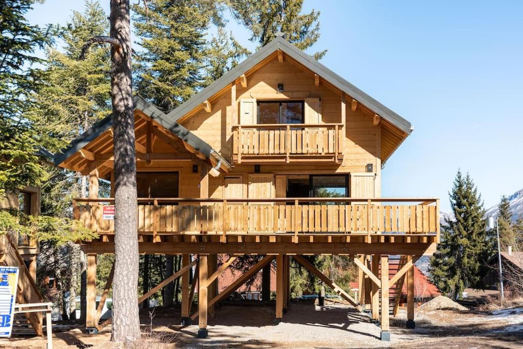 une cabane en rondins avec une terrasse dans les bois dans l'établissement Chalet perché Chabanon - Alpes du Sud, à Selonnet