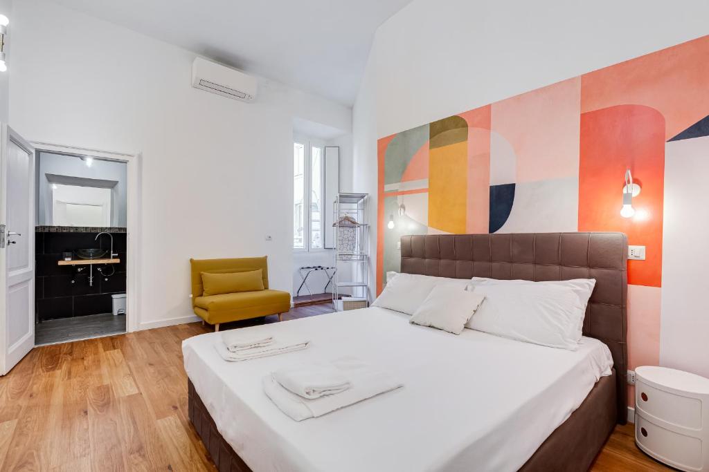 een slaapkamer met een bed en een gele stoel bij BMGA l Central Holiday House 2Bdr near Vatican in Rome