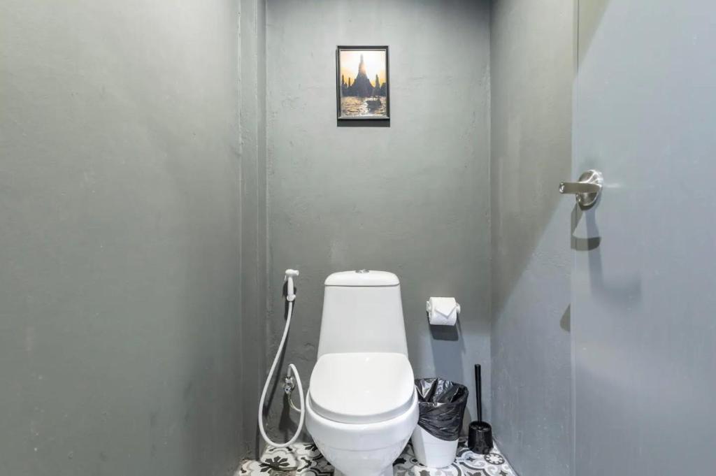 a bathroom with a toilet and a picture on the wall at Tuk Tuk House 250m from MRT Sirikit in Bangkok
