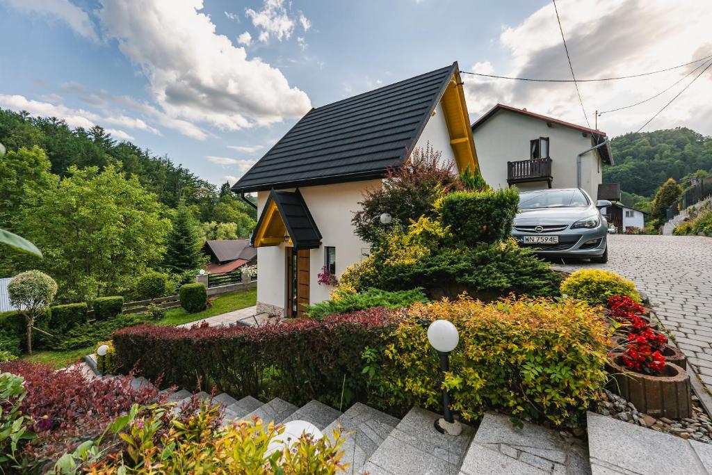 a house with a car parked in the driveway at Domek RogatY in Szczawnica