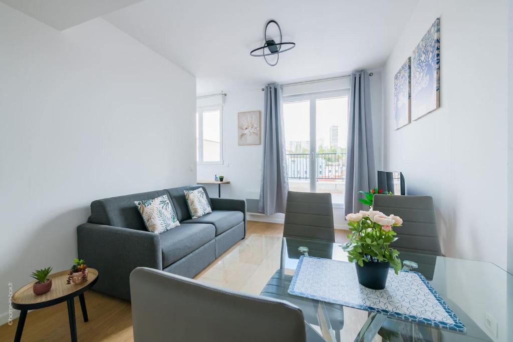 Cosy Appart Proche Paris في مونتروي: غرفة معيشة مع أريكة وطاولة