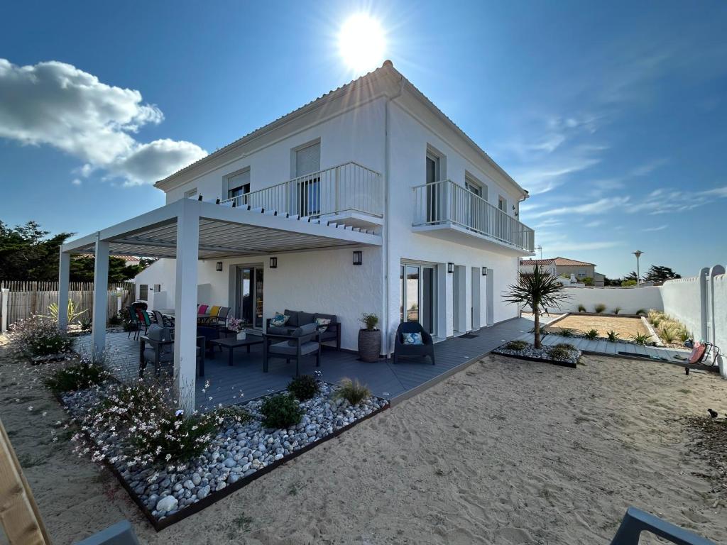 ein weißes Haus mit einer Terrasse am Strand in der Unterkunft 12 pers, sur la dune, PMR, spa, hammam, salle de sport in Barbâtre