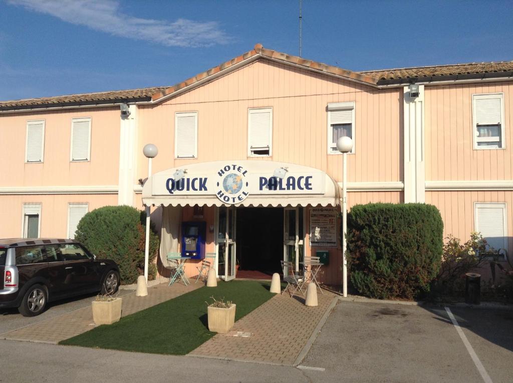 un bâtiment avec une voiture garée devant lui dans l'établissement Quick Palace St Jean De Vedas - A709, à Saint-Jean-de-Védas