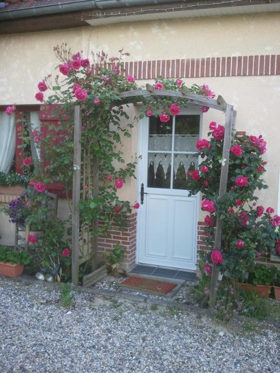 une porte blanche avec des fleurs sur le côté de la maison dans l'établissement Les Blancarts, à Hautebut