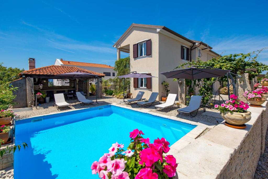 a villa with a swimming pool and a house at Apartments Bugenvila Brzac in Brzac
