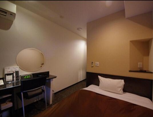 a bedroom with a bed and a desk with a mirror at Urbain Hiroshima Executive in Hiroshima