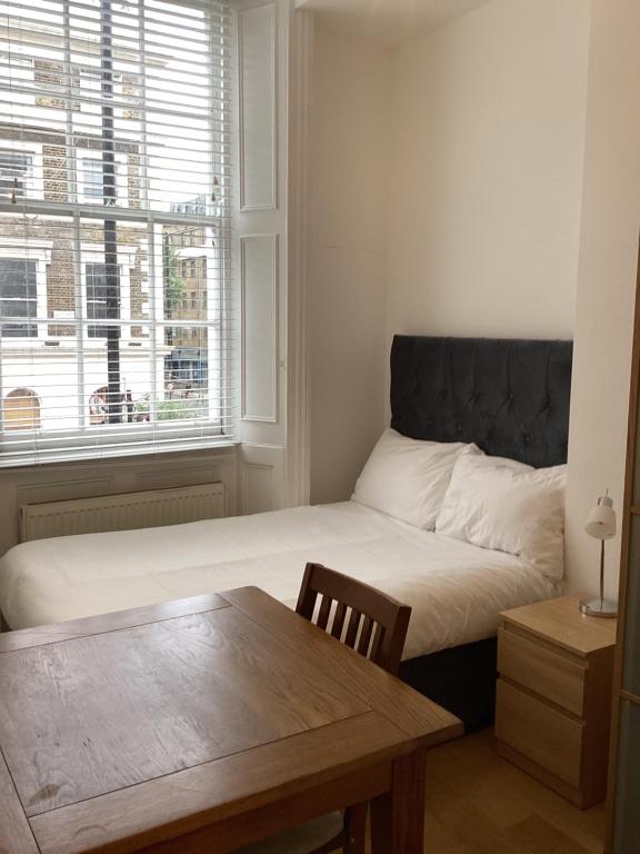 a bedroom with a bed with a table and a window at Central London Rooms in London
