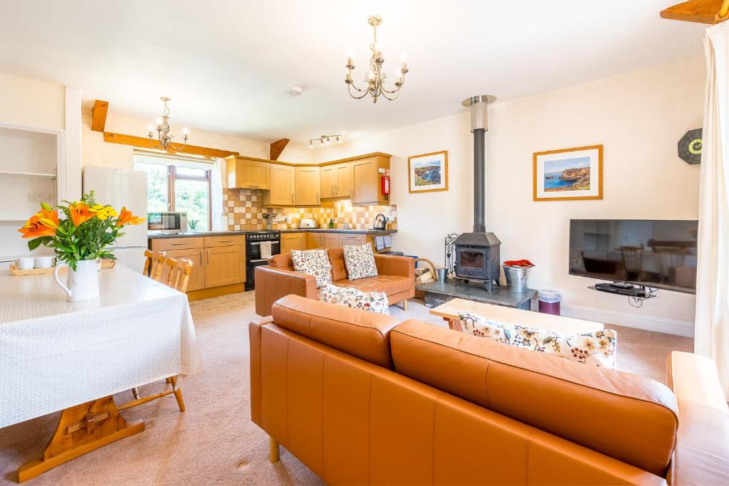 a living room with a couch and a table and a kitchen at Cargurra Farm in Boscastle