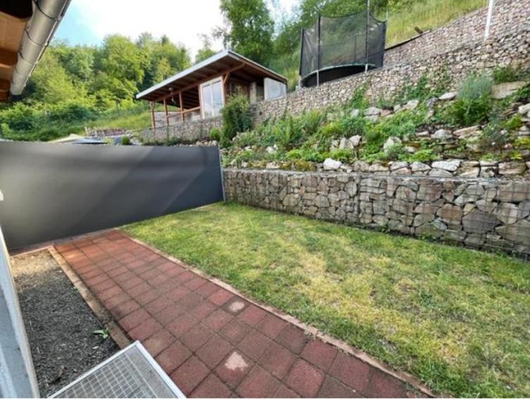 a garden with a stone wall and a brick walkway at Ferienwohnung Idarblick in Idar-Oberstein