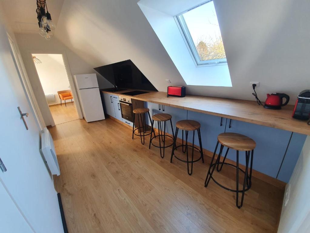 a kitchen with a counter and stools in a room at Granne de Lin étage in Tourville