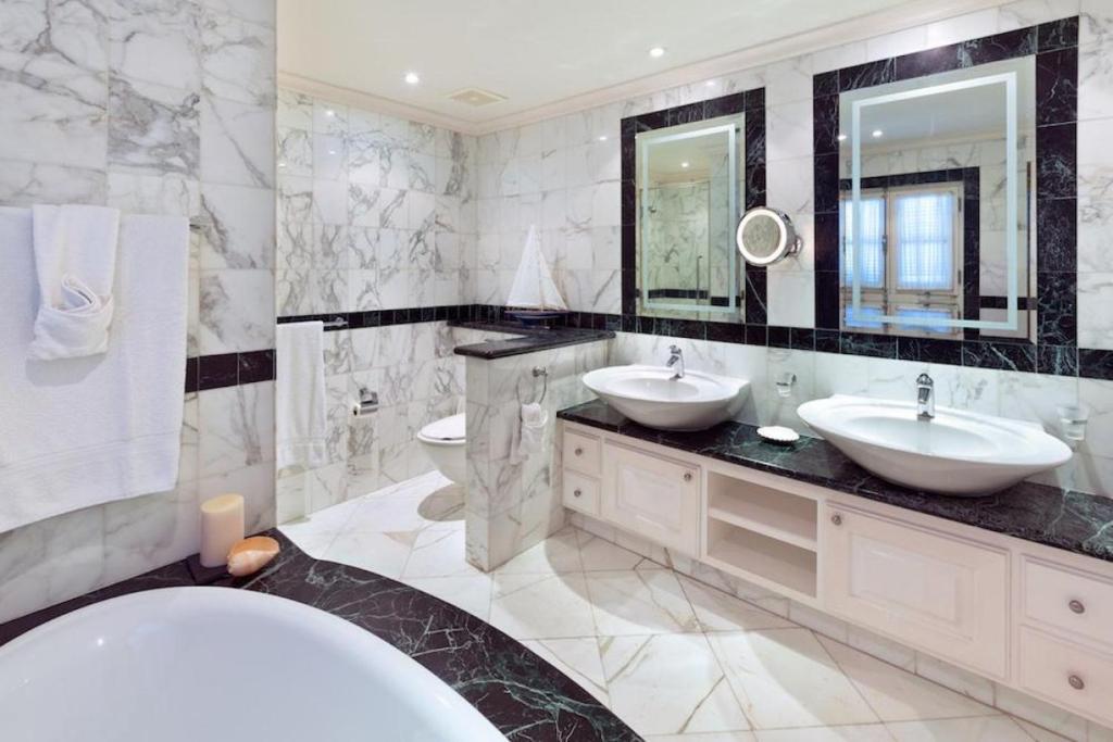 Sunny Vacation Villa No 15 في سانت بيتير: حمام أبيض مع مغسلتين وحوض استحمام