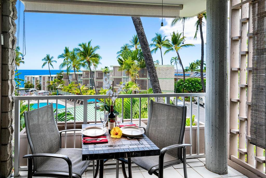 a table and chairs on a balcony with a view of the ocean at Alii Villas 309 in Kailua-Kona