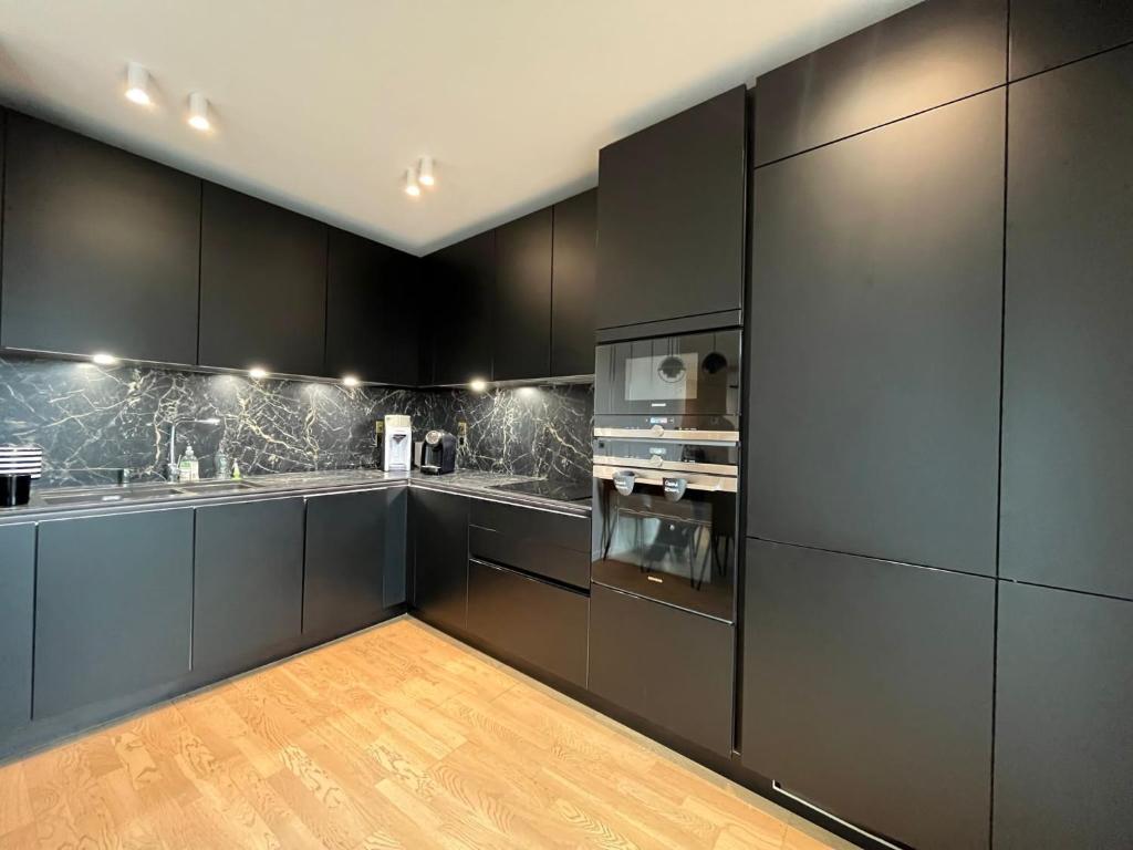 a kitchen with black cabinets and stainless steel appliances at Appartement Luxueux 3 pièces climatisé avec Terrasse, 5 couchages - 17ème Arrondissement de Paris in Clichy