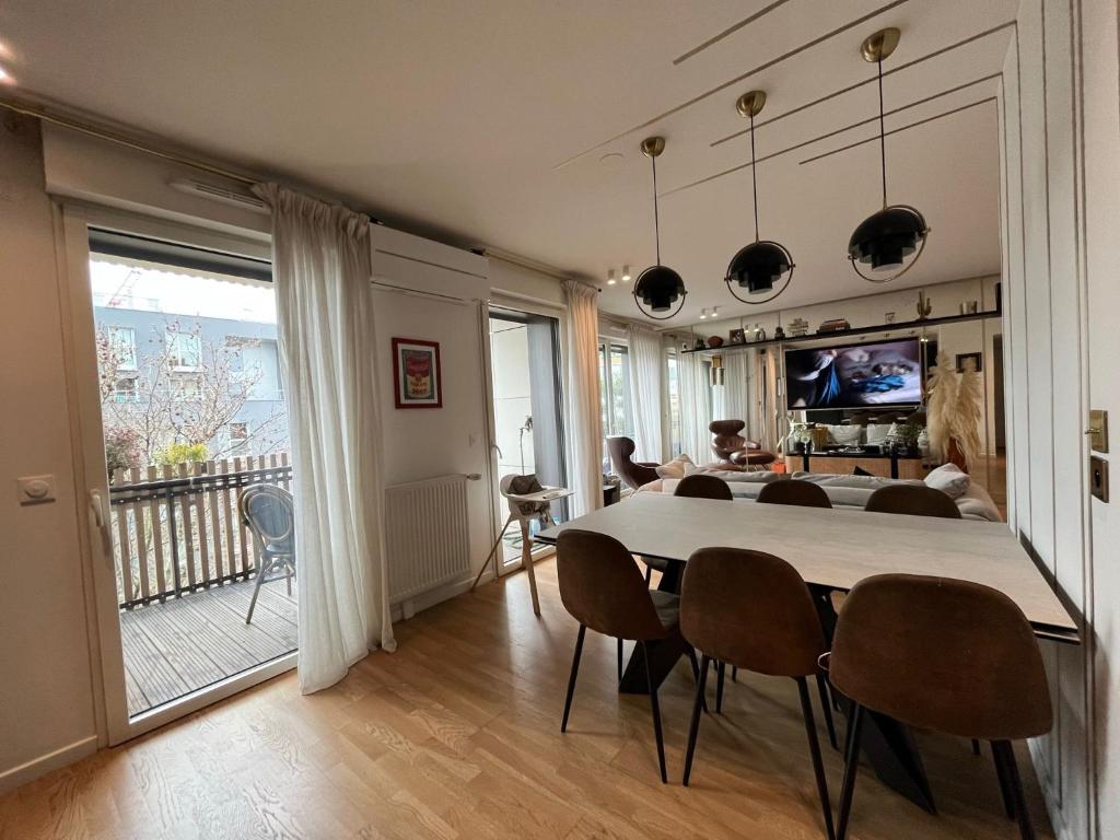 a dining room and living room with a table and chairs at Appartement Luxueux 3 pièces climatisé avec Terrasse, 5 couchages - 17ème Arrondissement de Paris in Clichy