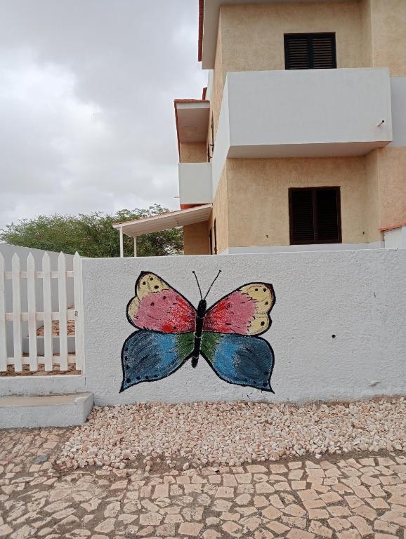 a butterfly painted on the side of a white fence at Farfalla in Vila do Porto