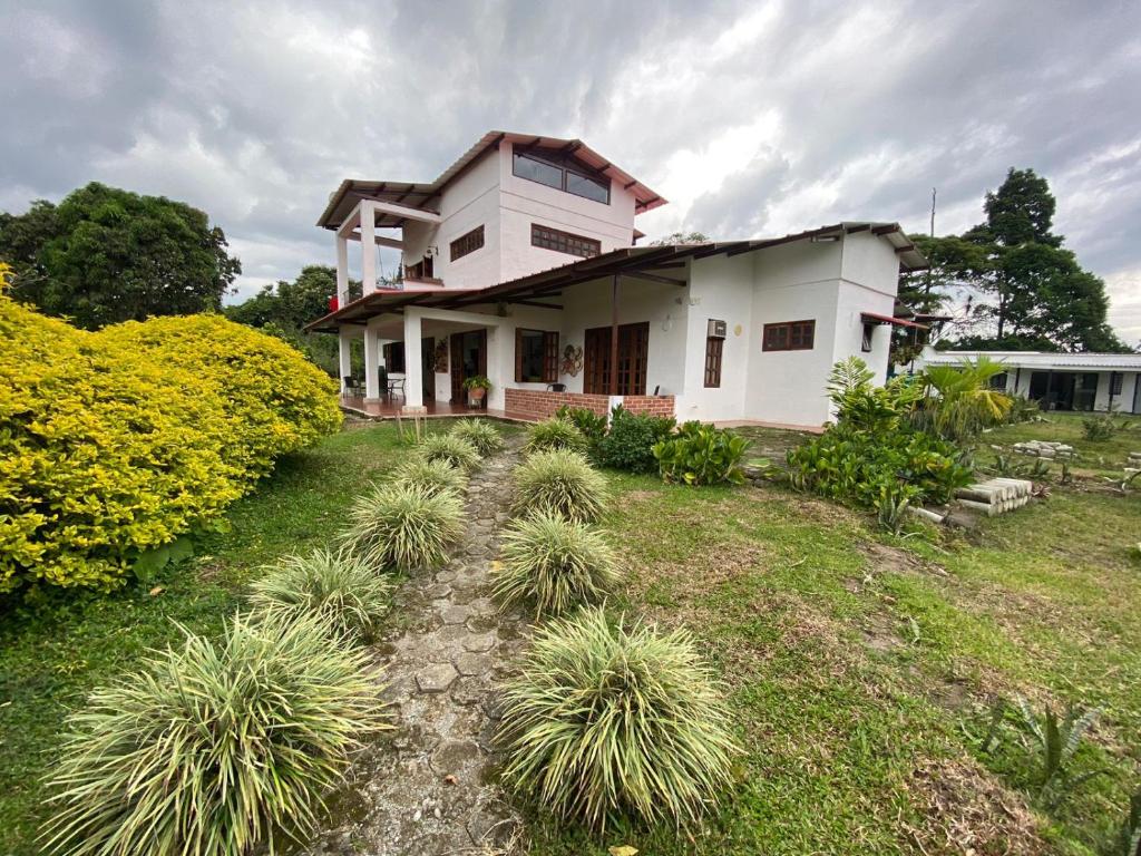 a white house with plants in the yard at Mi Casita Campersite in Armenia
