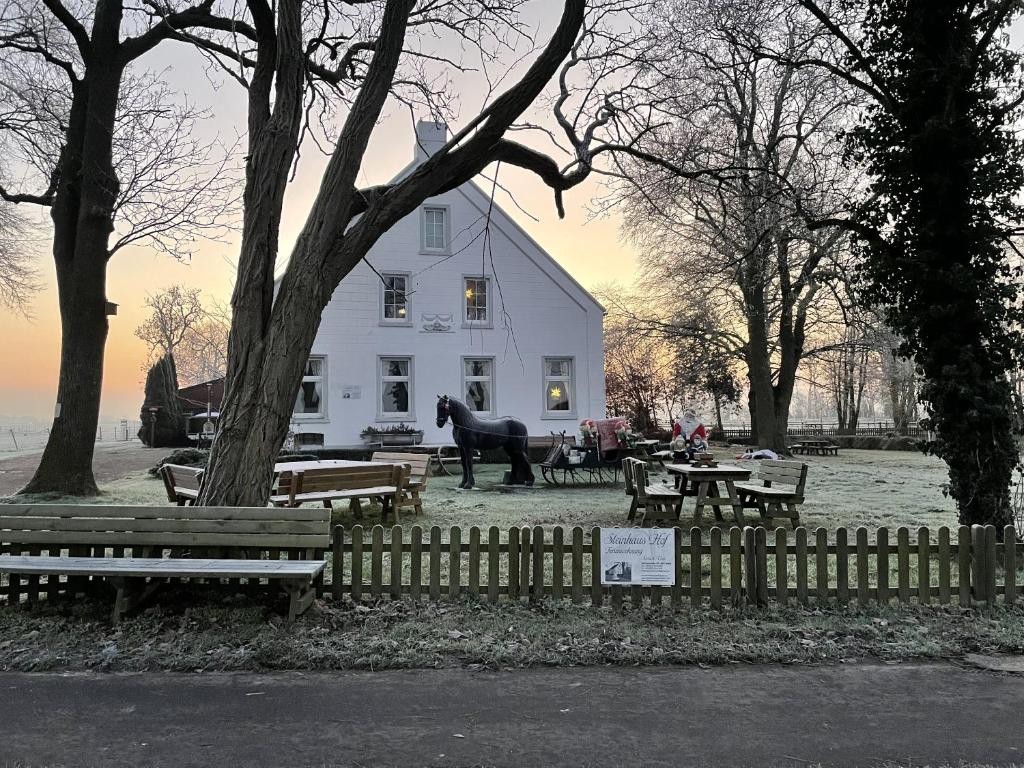 a horse statue in front of a white building with benches at Steinhaus Hof in Bunde