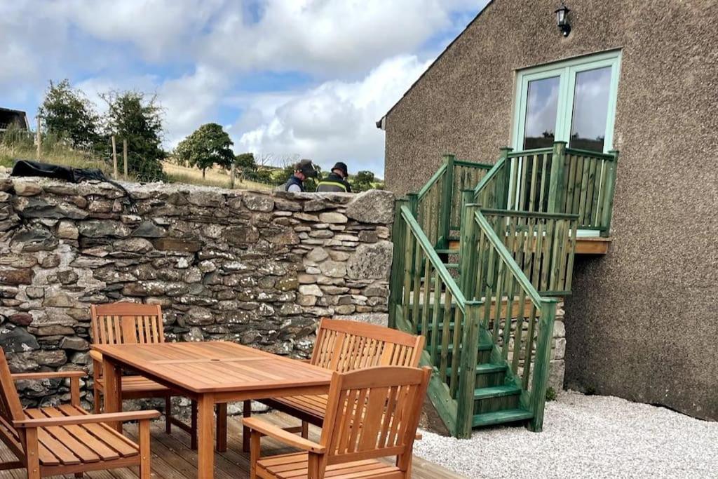 a wooden table and chairs next to a stone wall at Braffin @ Fellside Farm, Pennington, Ulverston in Pennington