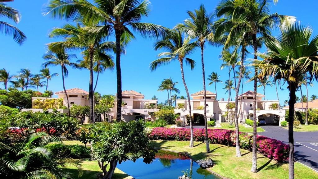 een uitzicht op een resort met palmbomen en een vijver bij The Shores at Waikoloa 231 in Waikoloa