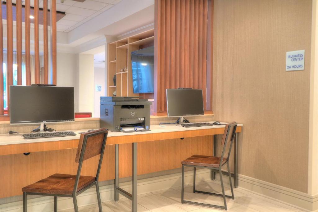 two chairs sitting at a desk with two computer monitors at Holiday Inn Express Hotel & Suites Mobile Saraland by IHG in Saraland