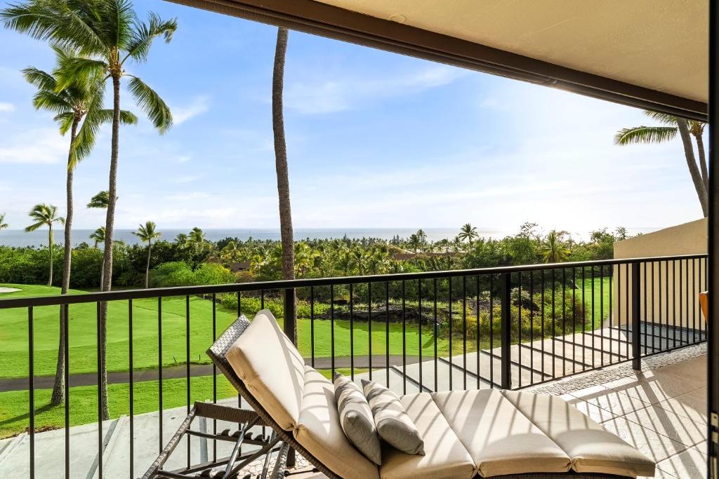 a balcony with a couch and palm trees at Country Club Villas 338 in Kailua-Kona