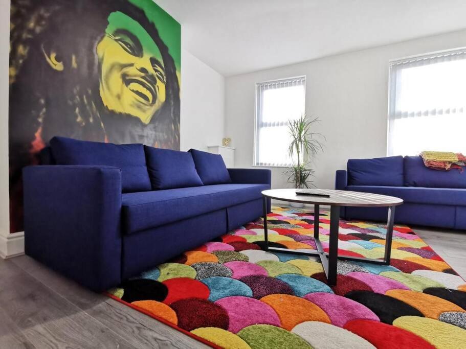 a living room with a blue couch and a colorful rug at The Bob Marley 'One Love' Apartment, Relaxed Vibes in Liverpool