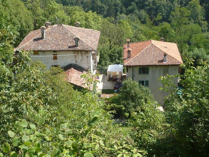 two houses with tiled roofs in a forest of trees at Cascina Gervasoni in Madonna della Costa