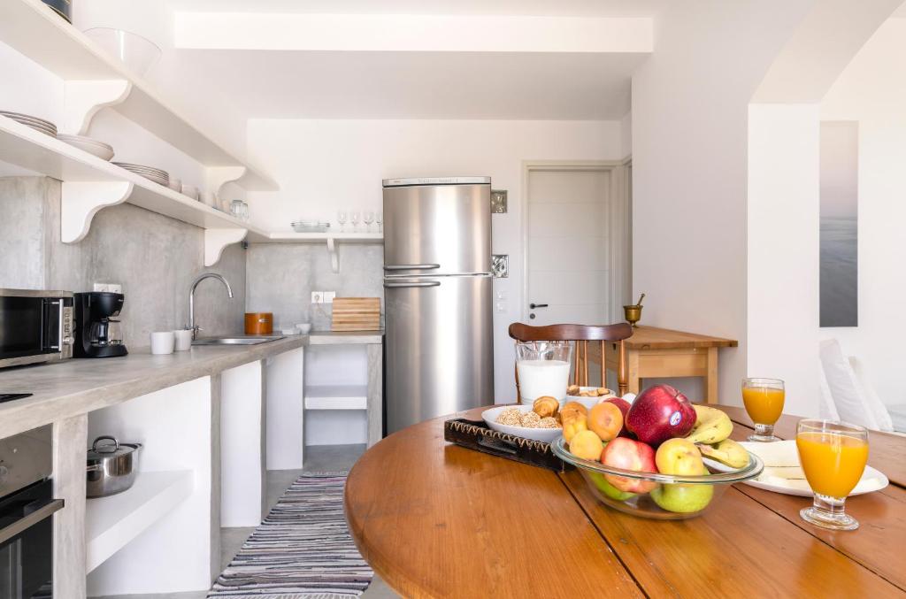 una cocina con una mesa de madera y un bol de fruta en Petrina Volia - Residence Anemos, en Ándros