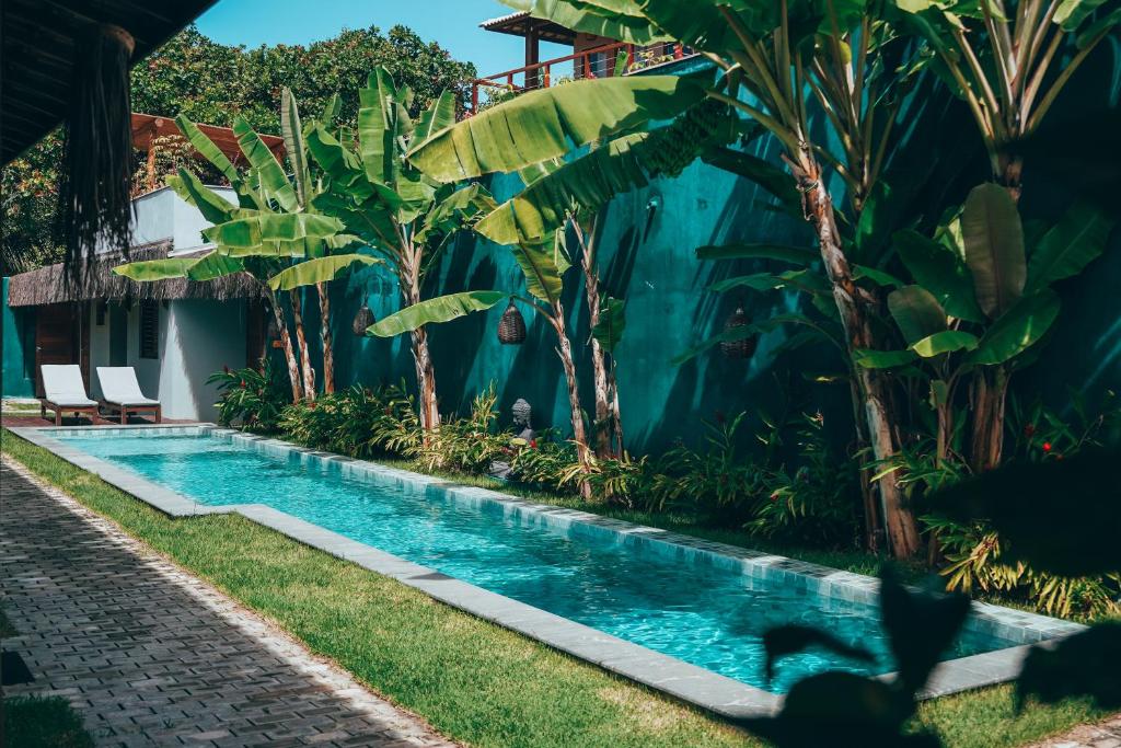 a swimming pool in front of a house with trees at Tropicália chalés boutique in Pipa