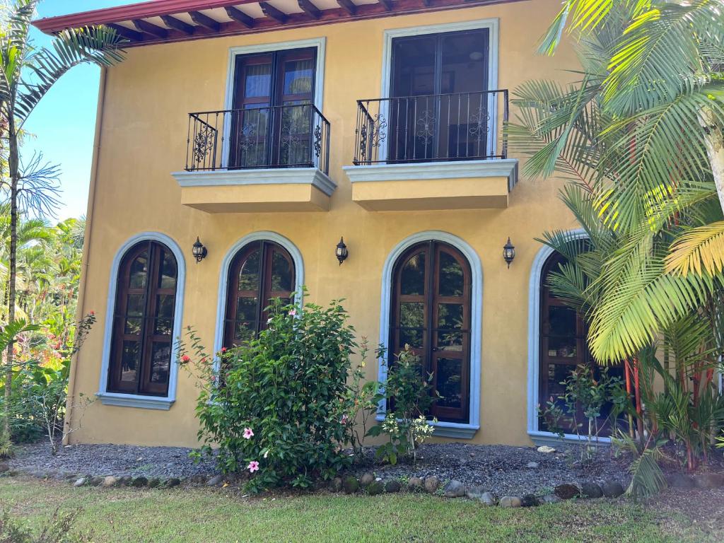 a yellow house with black windows and a balcony at Pavones Beach Resort in Pavones