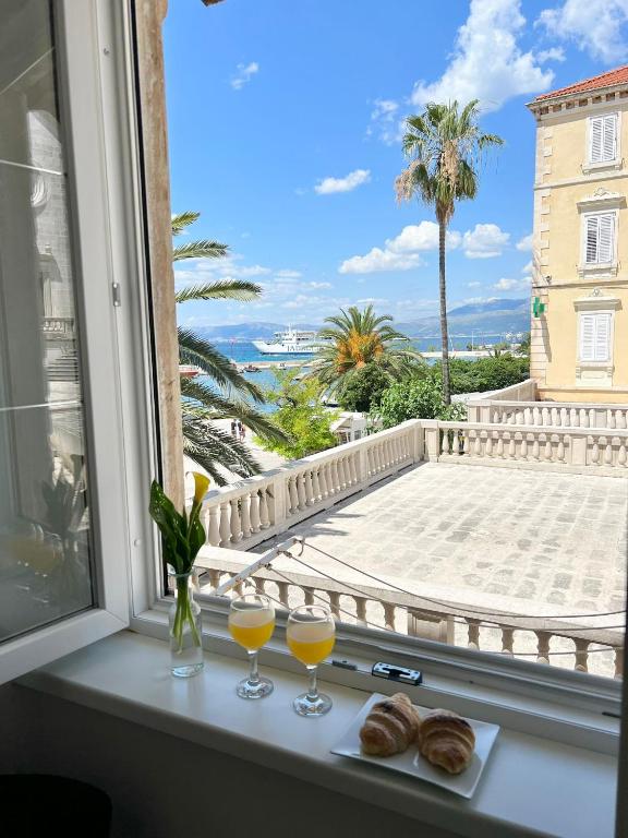 a view from a window with two glasses of orange juice at Luxury apartment Aura in Supetar
